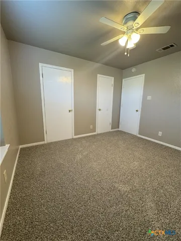 an empty room with a chandelier fan and windows