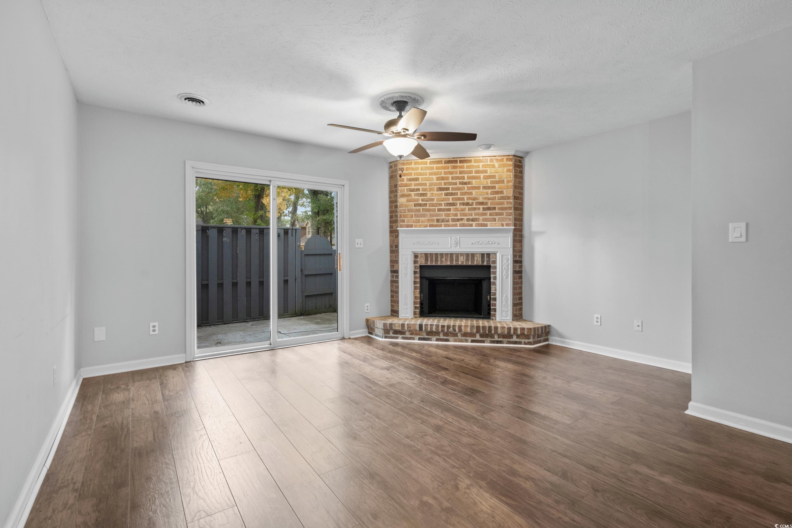 830 44th Avenue North, Unit X5 Myrtle Beach, SC 29577 - Photo 5 of 40 Unfurnished living room featuring a textured ceiling, ceiling fan, dark hardwood / wood-style flooring, and a fireplace