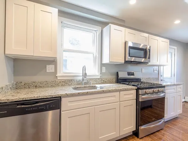a kitchen with granite countertop white cabinets and a stove top oven