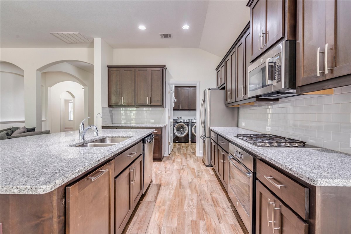 5009 Inks Clearing Lane Austin, TX 78738 - Photo 19 of 34 Rich wood cabinetry and speckled granite countertops define this modern, functional kitchen workspace.