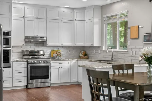 a kitchen with stainless steel appliances granite countertop a stove and white cabinets
