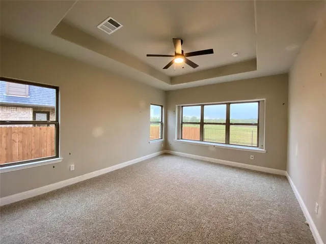 an empty room with chandelier fan and windows