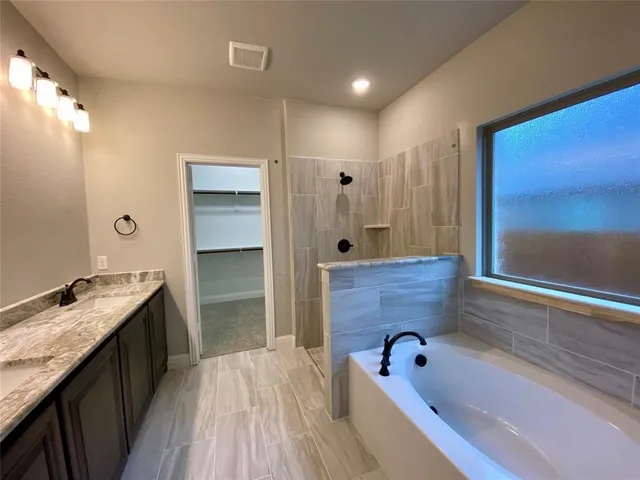 a bathroom with a granite countertop sink a bathtub and shower