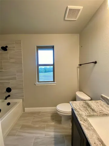 a bathroom with a granite countertop sink a toilet and bathtub