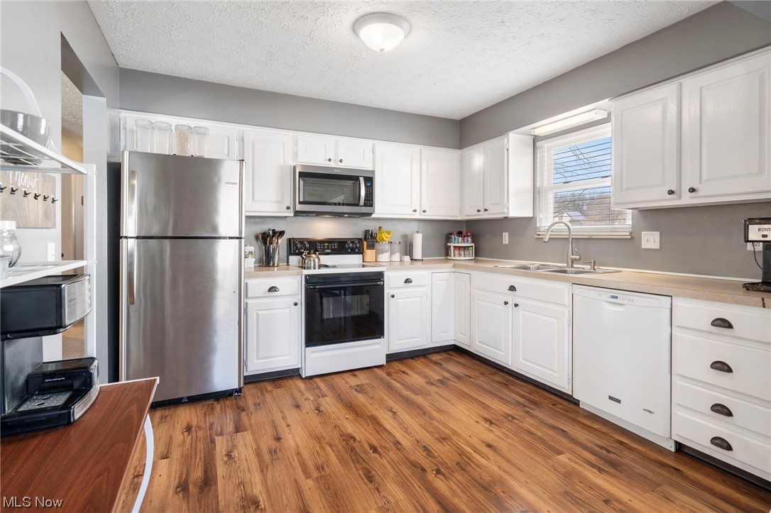 801 Netherwood Avenue Northwest Canton, OH 44708 - Photo 11 of 44 Kitchen featuring lvt wood-style floors, white cabinets, sink, and refrigerator with stainless steel finish