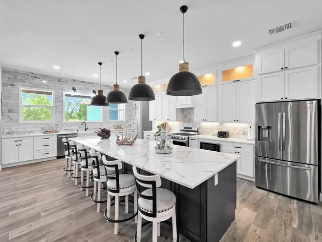 a kitchen with stainless steel appliances kitchen island granite countertop a table chairs and a sink