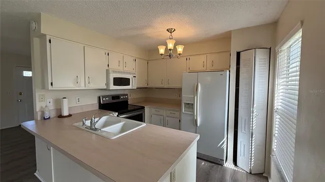 a kitchen that has a refrigerator a stove and white cabinets with wooden floor