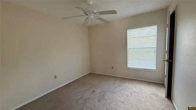 an empty room with a window and a fan