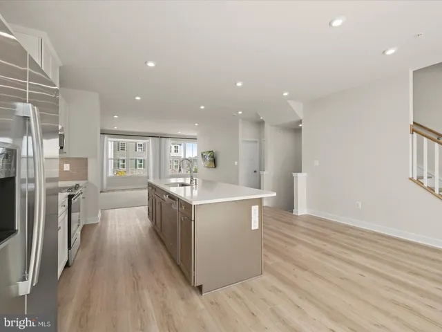 a view of a livingroom with wooden floor and kitchen view