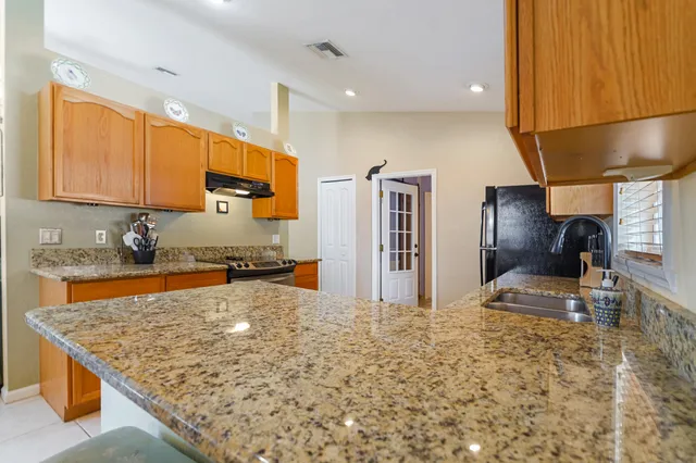 a kitchen with stainless steel appliances granite countertop a sink refrigerator and cabinets