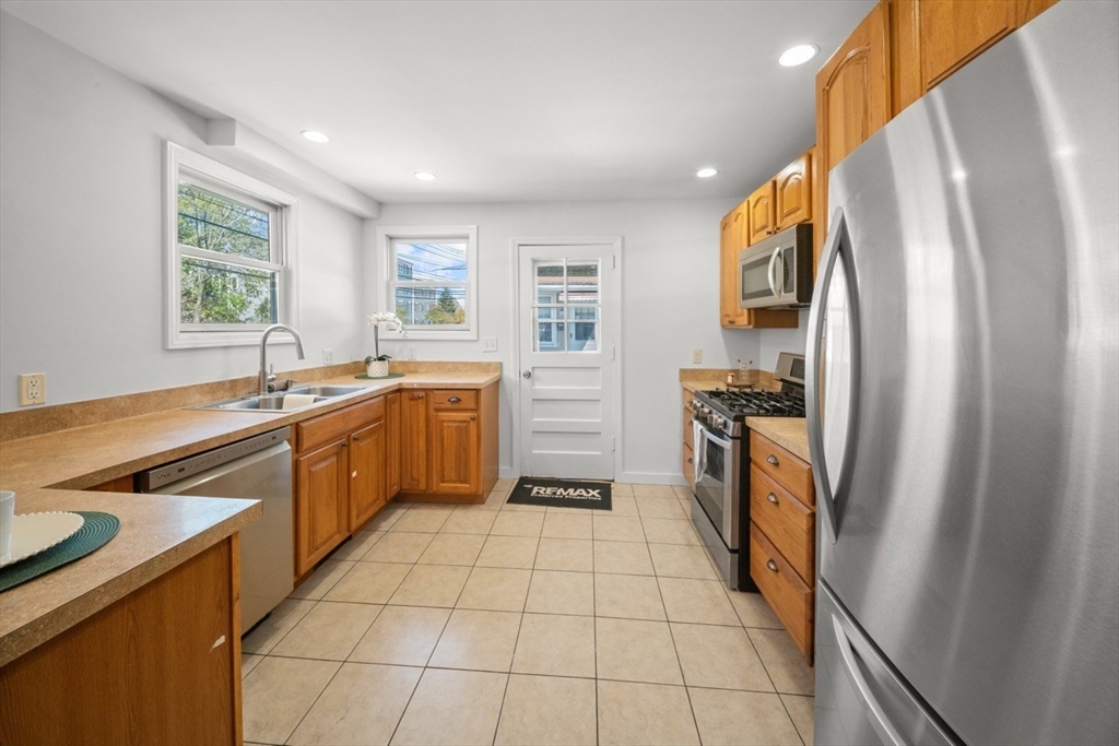 1180 Main Street, Unit 1 Waltham, MA 02451 - Photo 9 of 30 a kitchen with a sink a refrigerator and cabinets