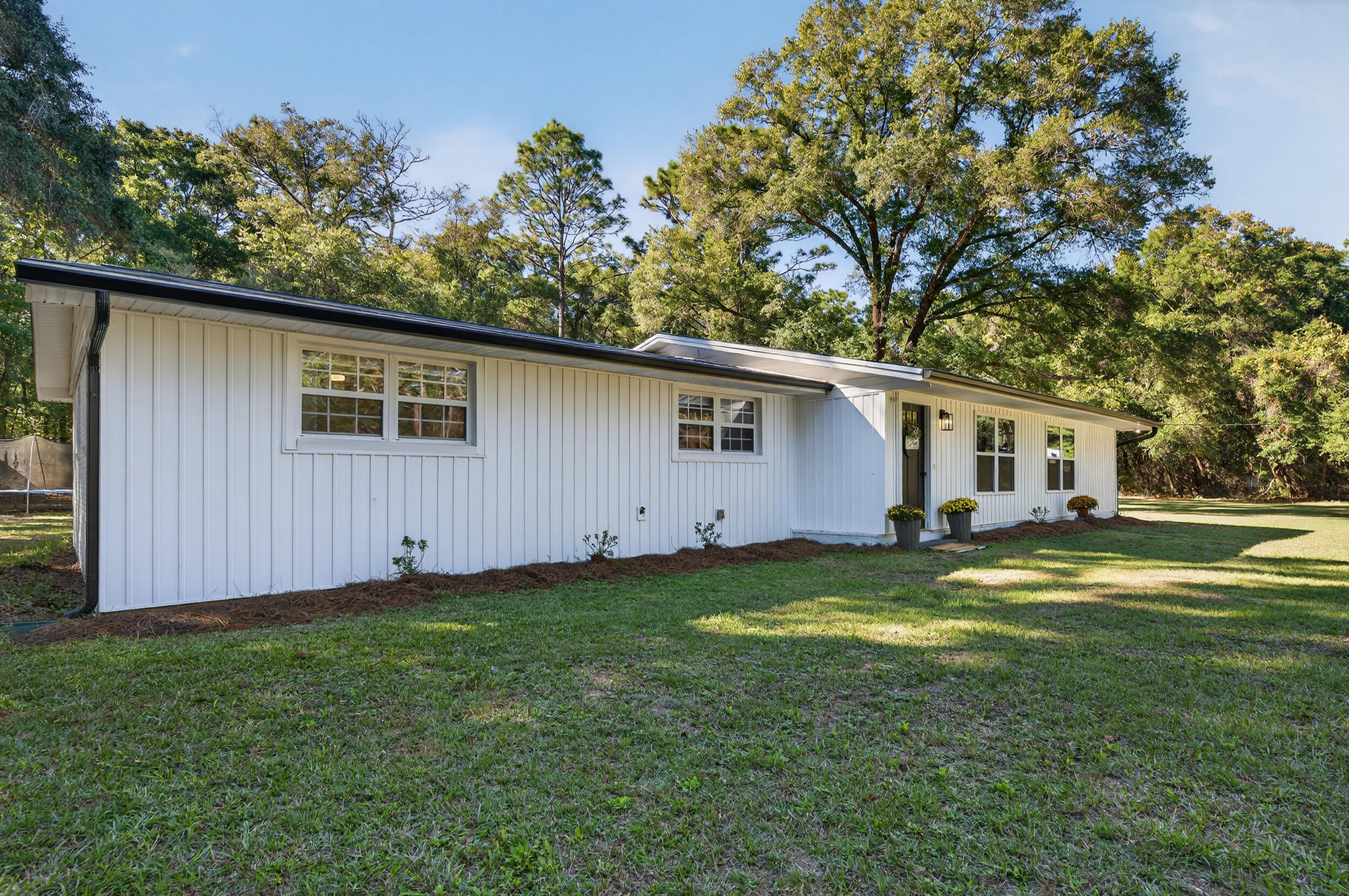 4734 Haybarn Road Holt, FL 32564 - Photo 1 of 54 a view of a backyard with plants and a large tree