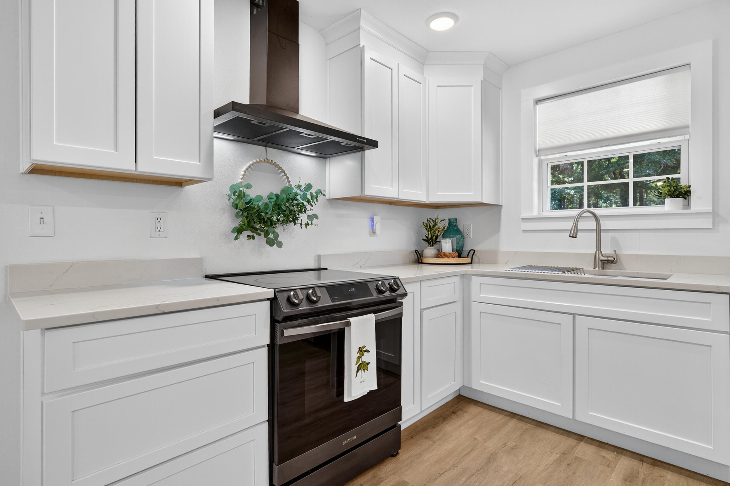 4734 Haybarn Road Holt, FL 32564 - Photo 12 of 54 a kitchen with white cabinets and a stove with wooden floor