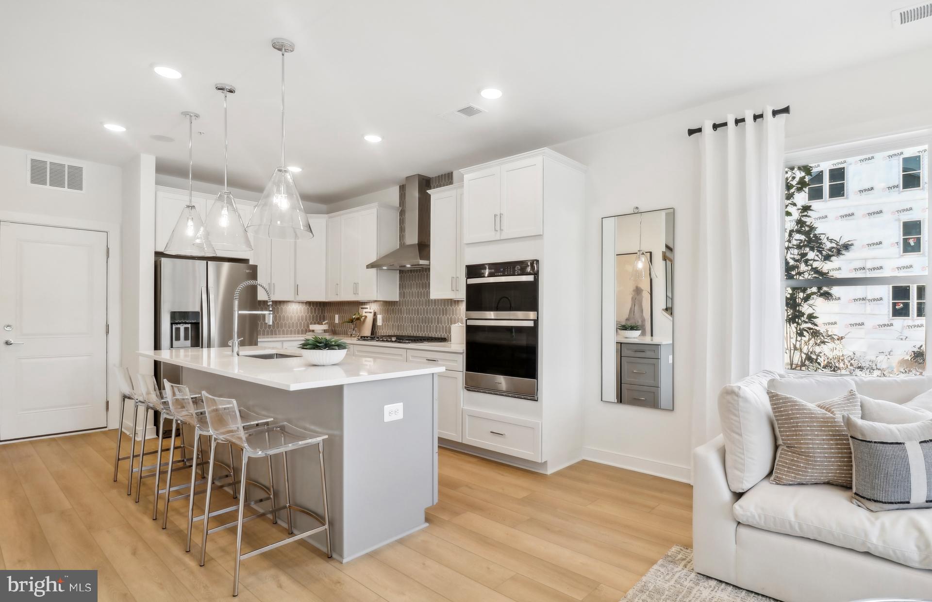 16144 Frederick Road Rockville, MD 20850 - Photo 5 of 32 a kitchen with stainless steel appliances kitchen island granite countertop a refrigerator a stove a sink a dining table and chairs with wooden floor
