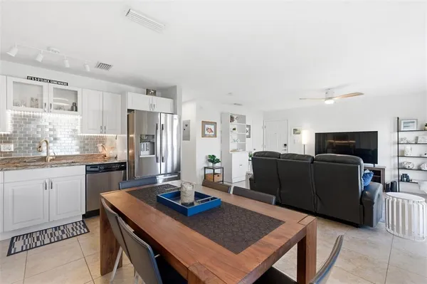 a kitchen with stainless steel appliances granite countertop a refrigerator a sink and white cabinets
