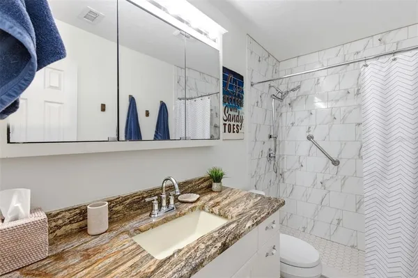 a bathroom with a granite countertop sink toilet and shower
