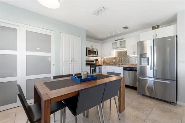 a kitchen with stainless steel appliances granite countertop a refrigerator a stove a sink a dining table and chairs