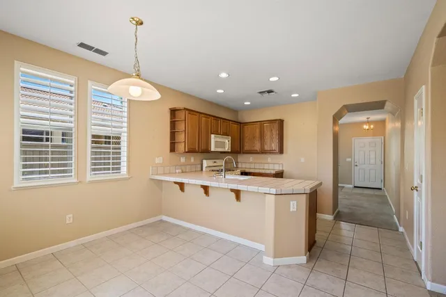 a kitchen with stainless steel appliances granite countertop a sink a stove a refrigerator and a window