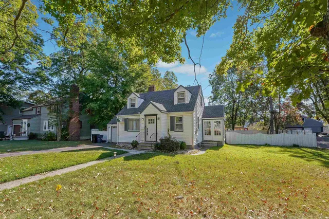 a front view of a house with a garden and trees