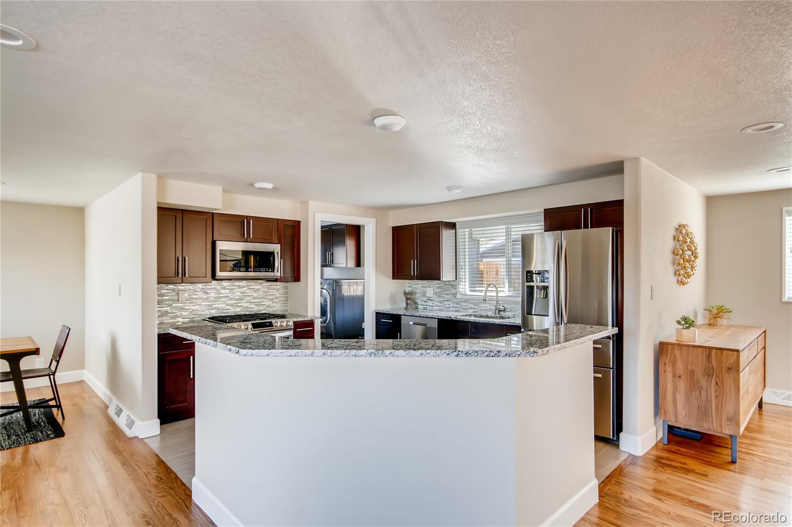 5655 Estes Street Arvada, CO 80002 - Photo 13 of 40 a kitchen with stainless steel appliances granite countertop a refrigerator and a stove top oven
