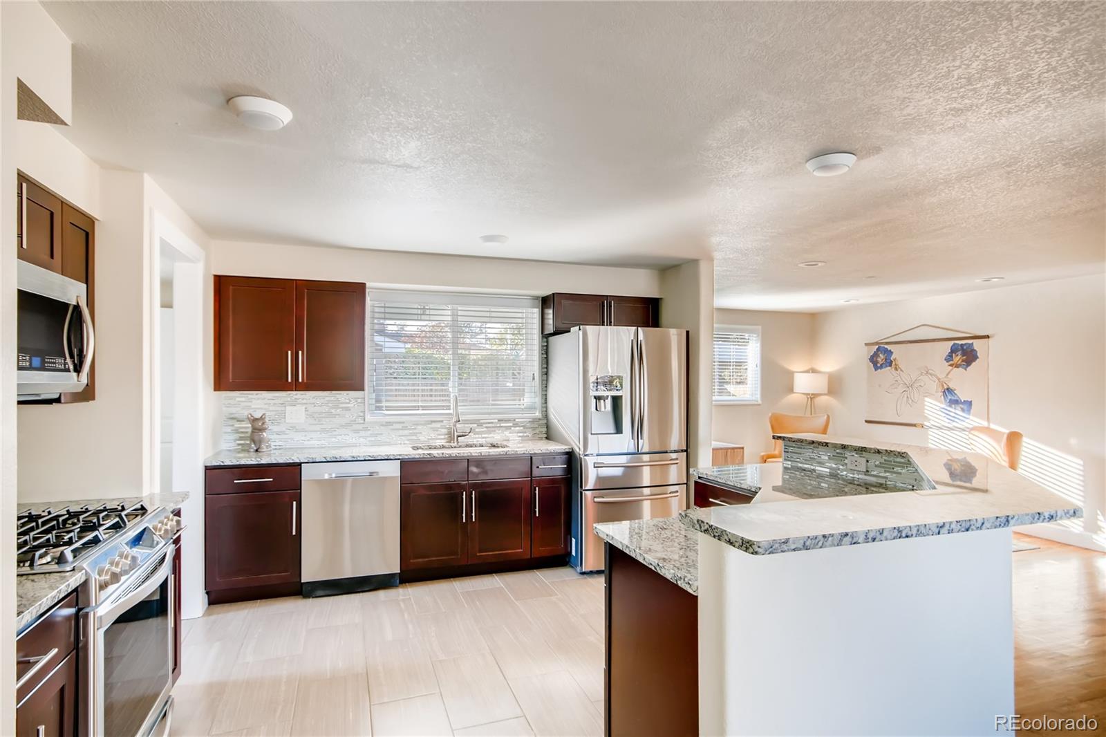 5655 Estes Street Arvada, CO 80002 - Photo 14 of 40 a kitchen with stainless steel appliances granite countertop a stove and a sink