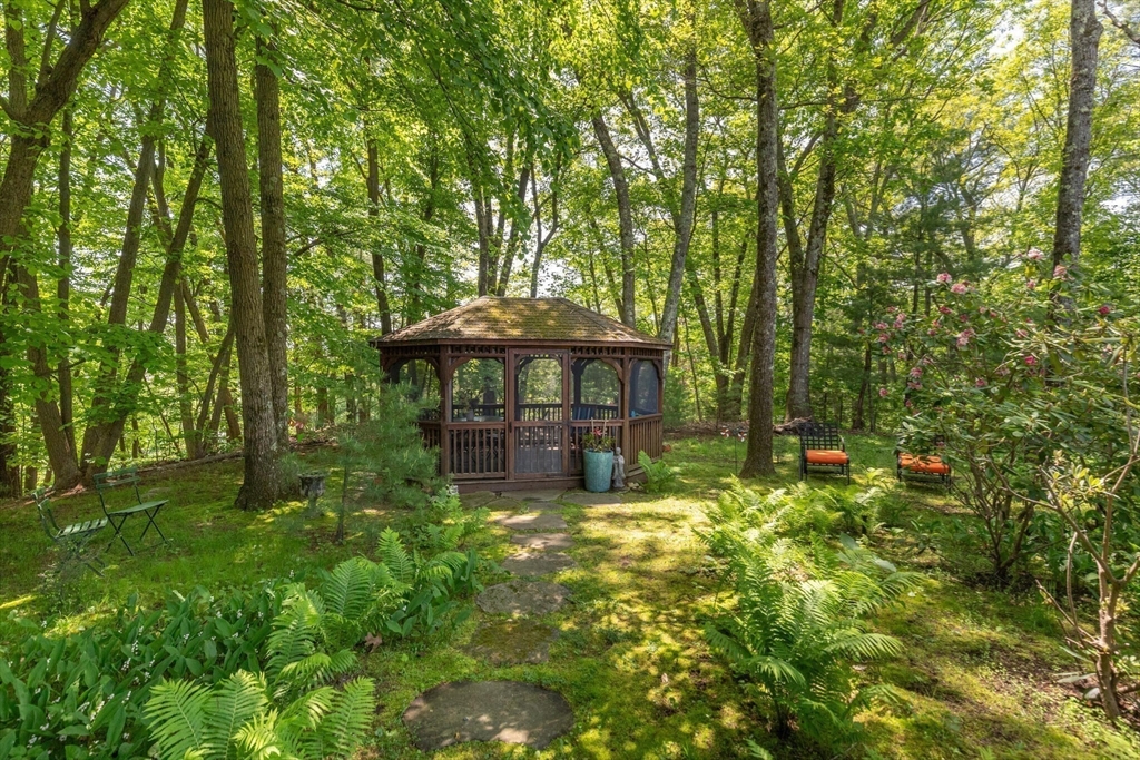 103 Revolutionary Road Concord, MA 01742 - Photo 33 of 36 a backyard of a house with table and chairs under an umbrella
