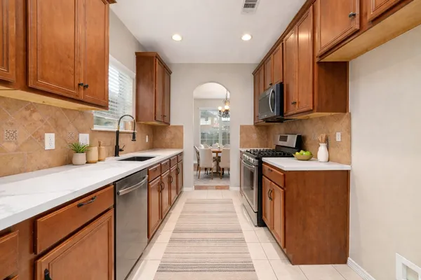 a kitchen with stainless steel appliances granite countertop a stove top oven a sink dishwasher and cabinets with wooden floor