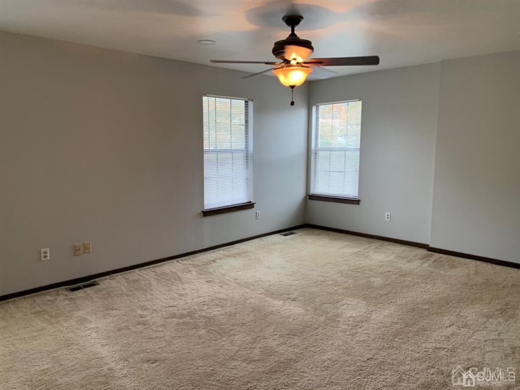 24 Pendleton Place Old Bridge, NJ 08857 - Photo 10 of 22 an empty room with a chandelier fan and a large window