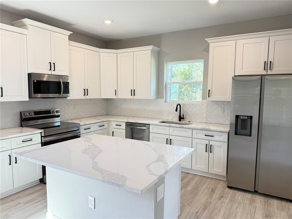 7815 Southwest 128th St Road Ocala, FL 34473 - Photo 9 of 40 a kitchen with stainless steel appliances a stove a sink and a refrigerator