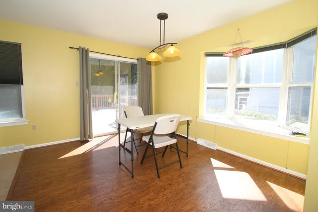 a dining room with wooden floor a chandelier a wooden table and chairs