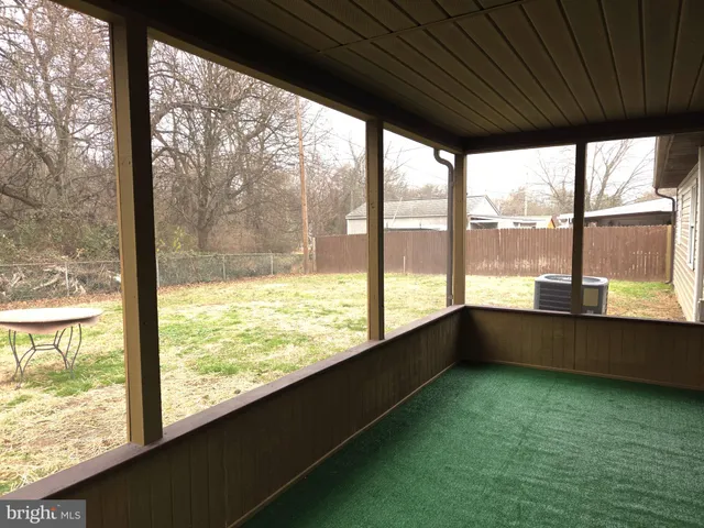 a view of an empty room with wooden floor and a large window