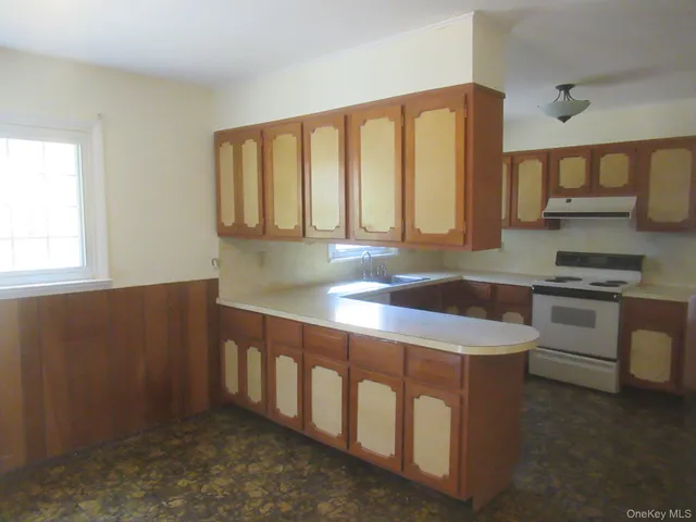 a utility room with stainless steel appliances granite countertop a sink a stove and a window