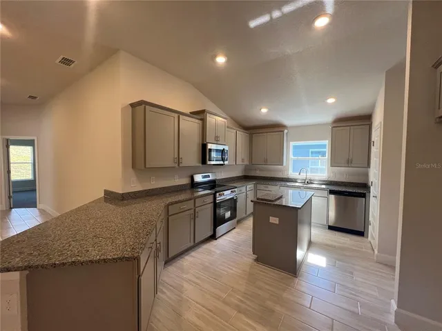 a large kitchen with a center island and stainless steel appliances