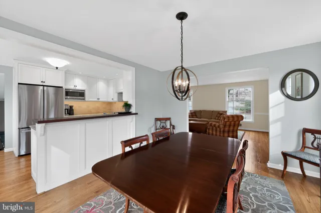 a kitchen with stainless steel appliances granite countertop a dining table chairs and a refrigerator