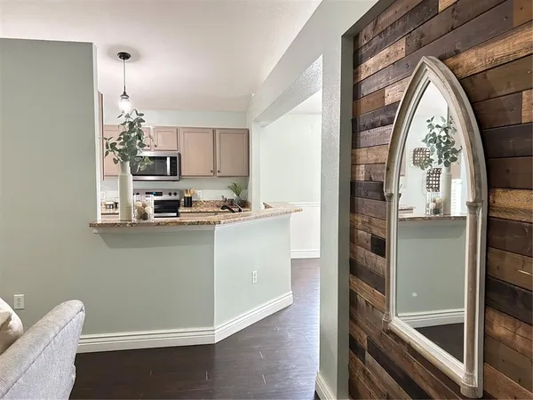 a kitchen with stainless steel appliances granite countertop a stove top oven a sink dishwasher a dining table and chairs with wooden floor
