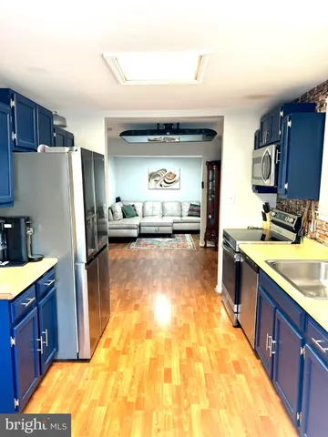 a large kitchen with kitchen island a large counter top and stainless steel appliances