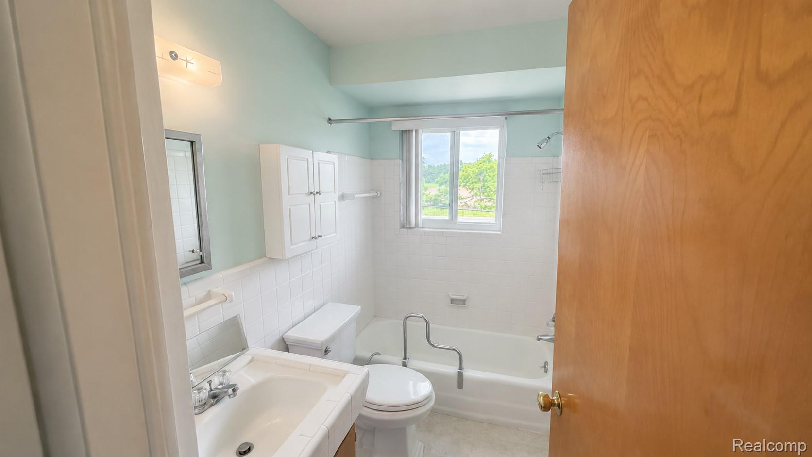 26945 Milford Road, Unit 34 New Hudson, MI 48165 - Photo 11 of 16 Bathroom featuring a built-in tub with shower, white subway tile surround, and a vanity with an integrated sink