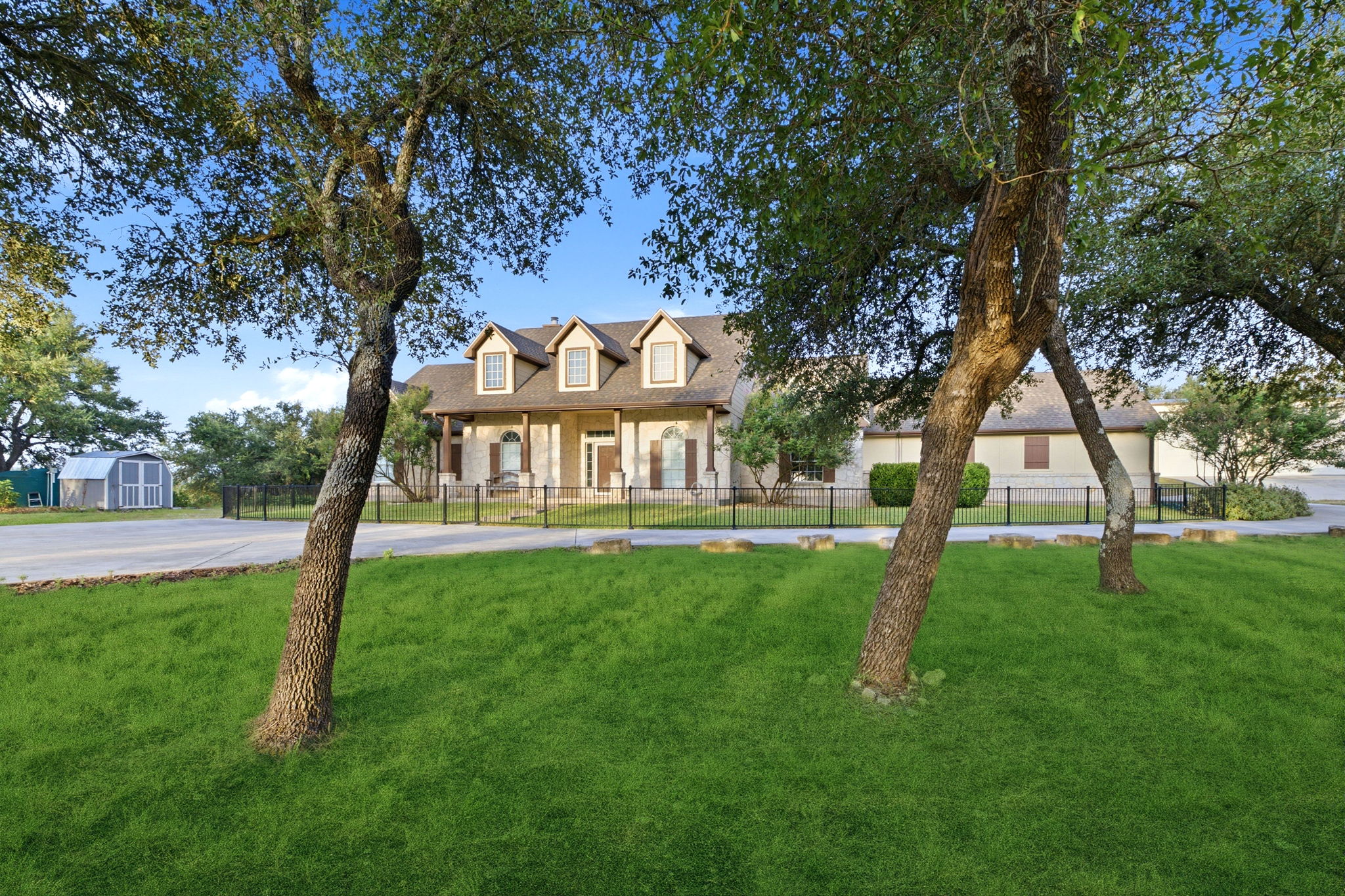 271 Rollin N Ranch Road Blanco, TX 78606 - Photo 5 of 40 A classic residence awaits behind a lush lawn, featuring a charming facade and a spacious, welcoming driveway.