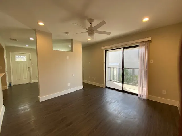 a view of an empty room with wooden floor and a window
