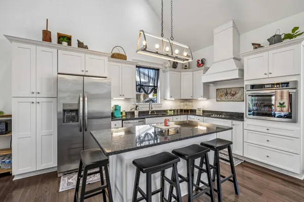 a kitchen with granite countertop a table chairs stainless steel appliances and cabinets