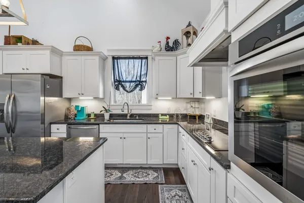 a kitchen with stainless steel appliances granite countertop a sink a stove and a refrigerator