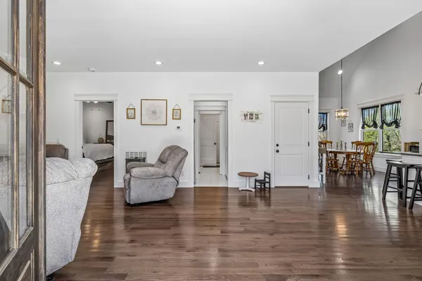 a living room with furniture and a dining table with wooden floor