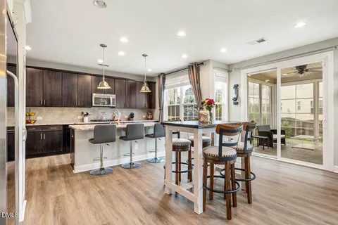a kitchen with stainless steel appliances kitchen island granite countertop a table chairs and a refrigerator