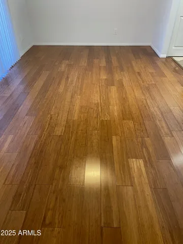 an empty room with wooden floor fan and windows