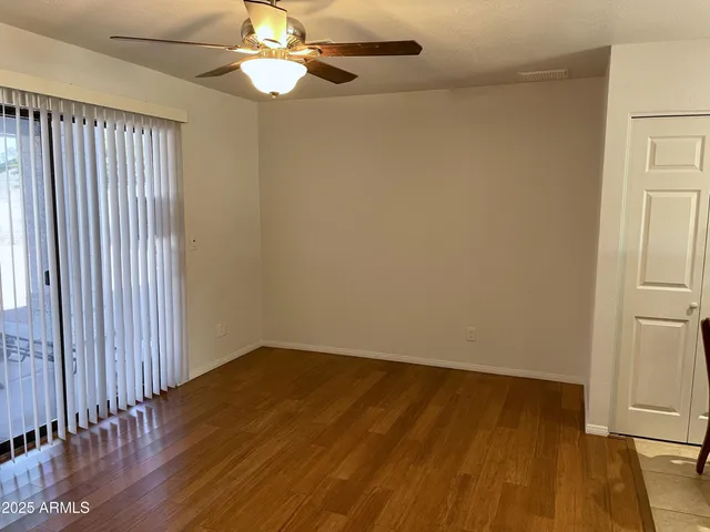 an empty room with wooden floor fan and windows