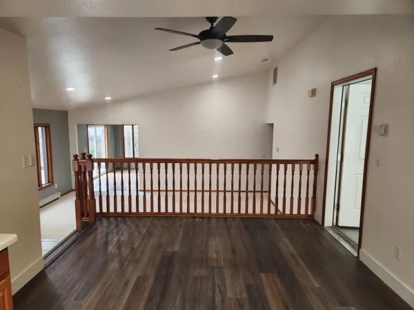 a view of a hallway with wooden floor and a ceiling fan