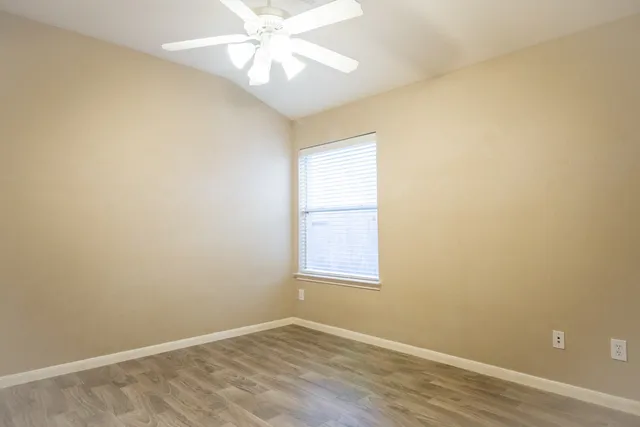 an empty room with a window and wooden floor
