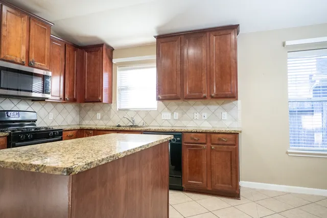 a kitchen with granite countertop cabinets stainless steel appliances a sink and a window