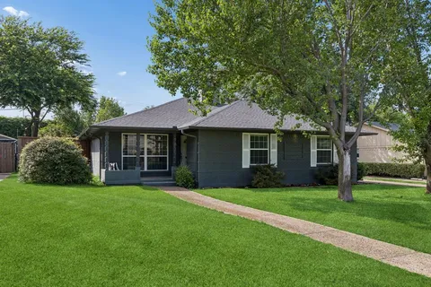a front view of a house with a garden and trees