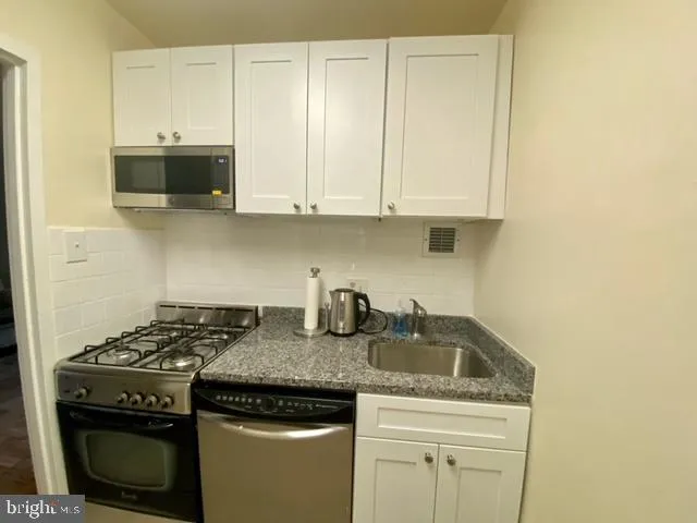 a kitchen with granite countertop a stove sink and cabinets